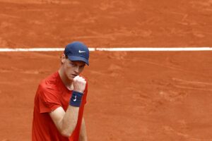 Jannik Sinner esulta alzando un pugno dopo aver vinto un punto sulla terra rossa di Parigi
