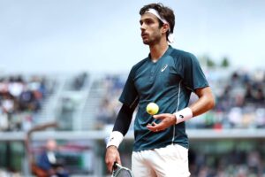 Lorenzo Musetti in campo al Roland Garros tiene in mano una pallina
