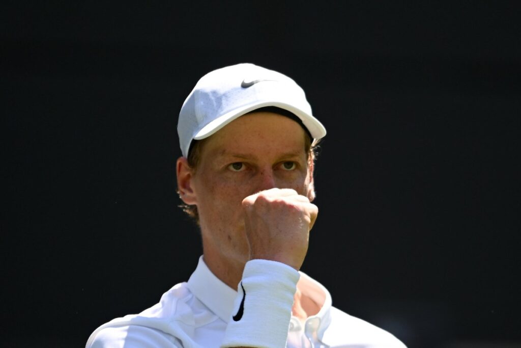 Primo piano di Sinner che esulta a pugno alzato sull'erba di Wimbledon