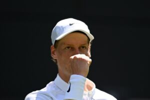 Primo piano di Sinner che esulta a pugno alzato sull'erba di Wimbledon